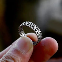 Bague viking homme tenue à la main, gravée de motifs nordiques entrelacés