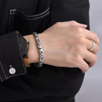 Bracelet en argent tendance porté au poignet d’un homme, bijou balinais élégant assorti à une montre noire.