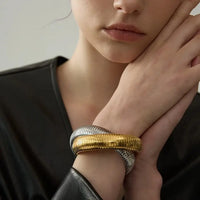 Bracelet Tubogas porté au poignet par une femme – bijou bicolore en acier inoxydable plaqué or et platine, style moderne et chic