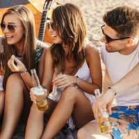 Groupe d’amis sur la plage arborant chacun un bracelet menotte – accessoire mode mixte pour représenter le lien et la complicité.