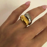 Main de femme portant une bague femme acier inoxydable bicolore dorée et argentée, au design bombé et contemporain.